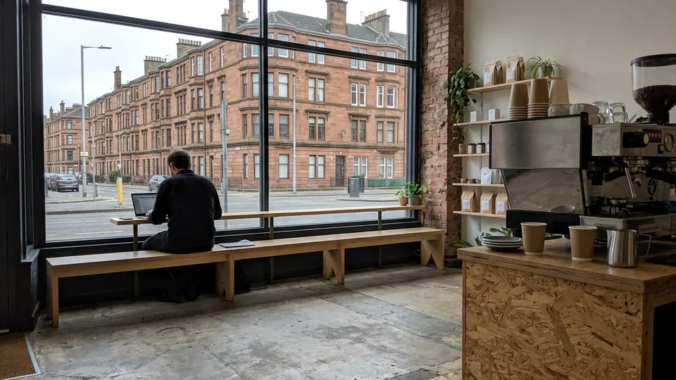 A long wooden bench under the big front window at Calder Coffee