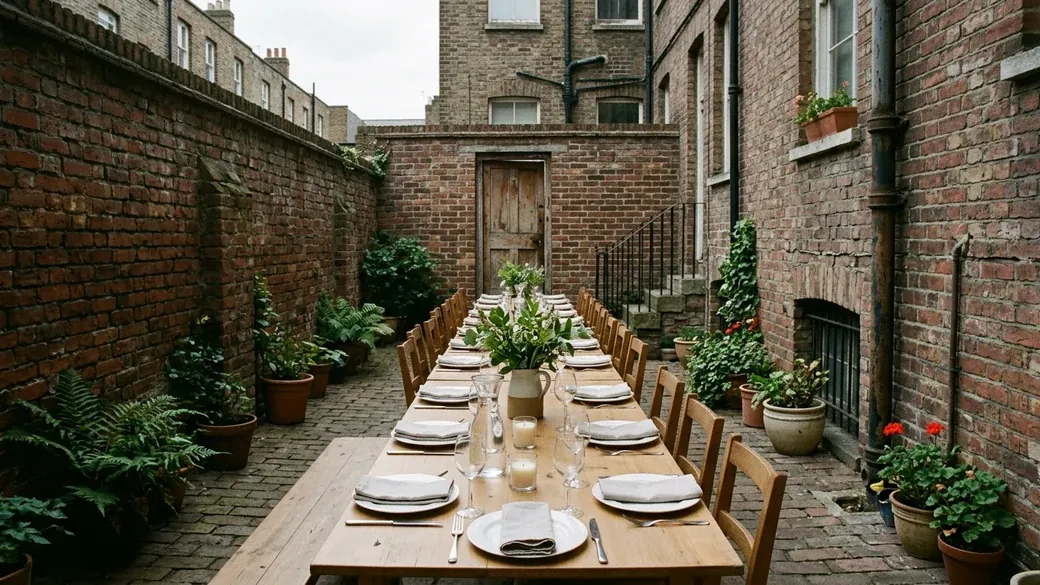 A long table laid for dinner in a brick courtyard, seen from one end