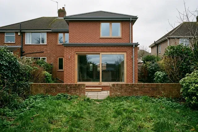 A brick house extension with tall timber windows seen from the garden